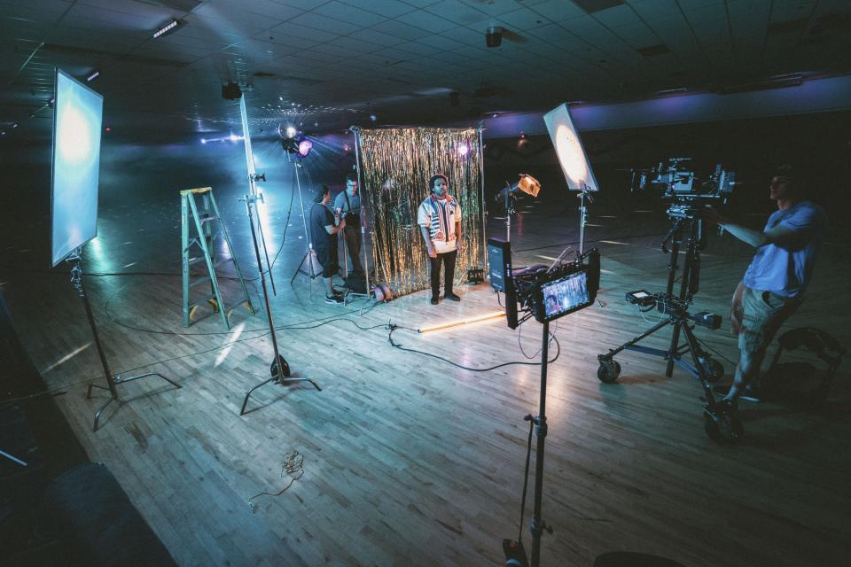 Il set di un videoclip: luci, cavalletti e una tenda dorata